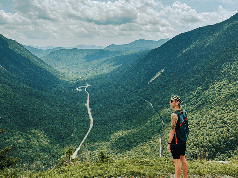 A man stands with the view from Mount Willard in the background