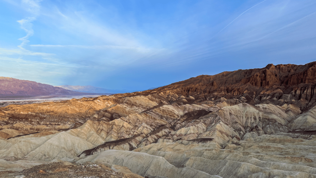 Dramatic landscape of the Badlands seen from the Gower Gulch Loop in Death Valley National Park during golden hour, showcasing the contrasting textures and colors of the eroded rock formations.