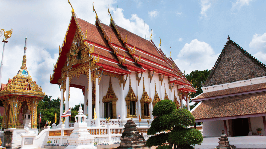 The intricate architecture of Chalong Temple in Phuket, featuring red and gold roofs, ornate decorations, and clear blue skies.