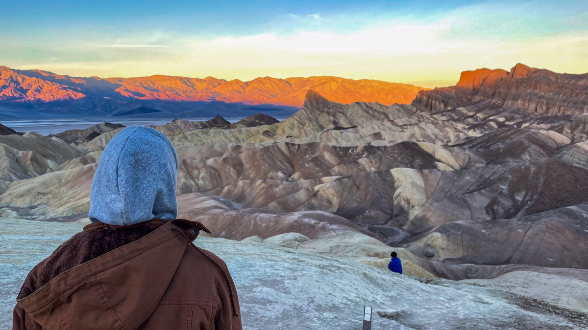 A man stands, looking away from the camera, during a sunrise in Death Valley National Park