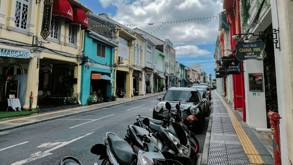 Vibrant street scene in Phuket Town with traditional Sino-Portuguese architecture, bustling with scooters, cars, and pedestrians