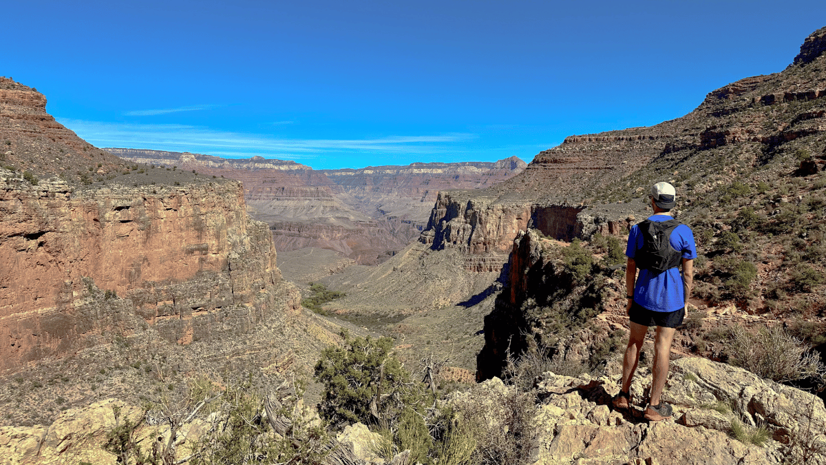 A man stands on a cliff edge staring out over Grand Canyon National Park