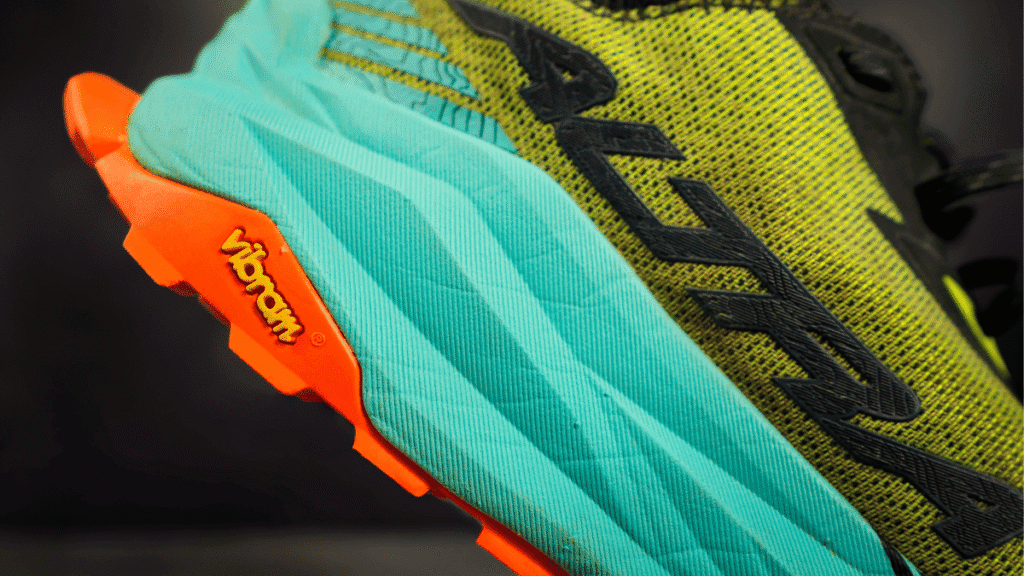 Close-up of the midsole and heel area of the shoe, highlighting the yellow Vibram logo on the orange outsole and black "Altra" branding on the upper.
