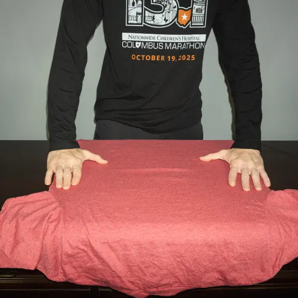 Red t-shirt smoothed out on a dresser, an important prep step before folding or rolling clothes for travel.