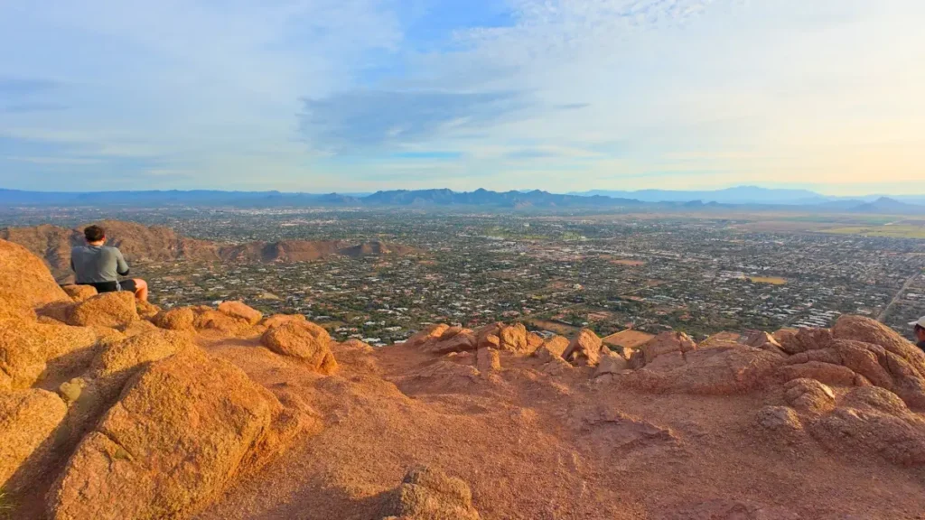A panoramic view from the summit after running Camelback Mountain, showing the sprawling Phoenix city skyline and surrounding desert valley.