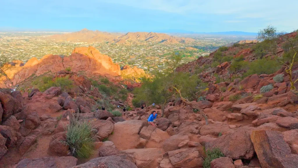 A runner navigating a steep rock face on the Echo Canyon Trail while running Camelback Mountain.