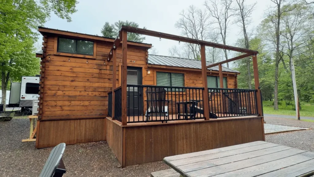 Modern black and wood-paneled tiny luxury cabin called The Peaceful Nook with a front deck at Seven Mountains Campground in Pennsylvania.