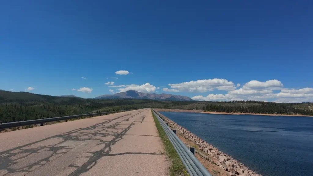 Paved dam road along Rampart Reservoir with Pikes Peak rising in the distance