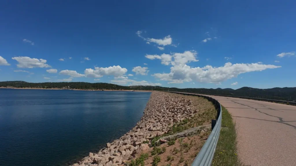 Dam access road curving along the riprap shoreline of Rampart Reservoir