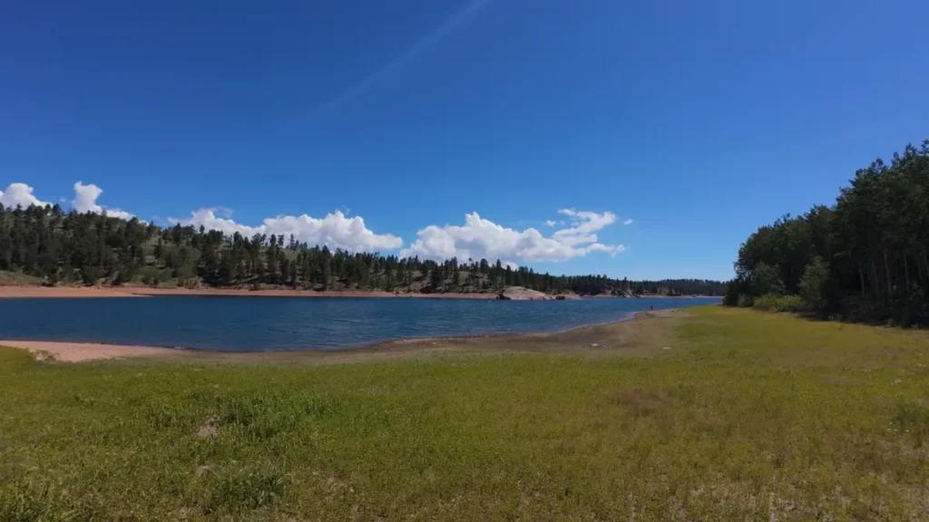 Open shoreline and sandy beach along Rampart Reservoir with the far tree line in view