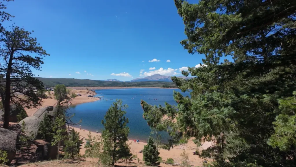 Overlook of Rampart Reservoir's swim beach and kayakers with Pikes Peak on the horizon