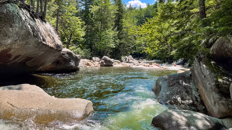 Natural swimming hole surrounded by boulders at Franconia Falls