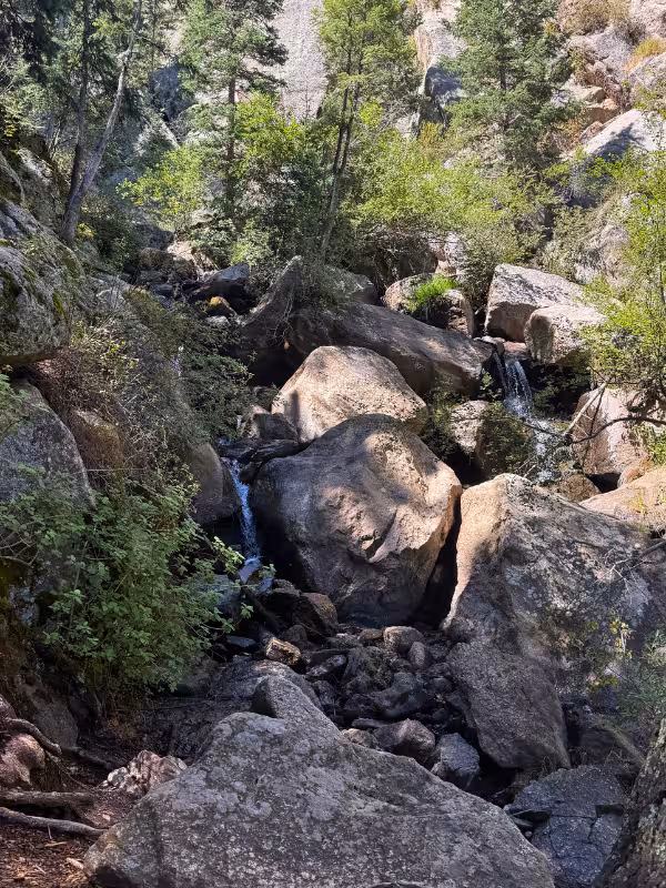 Light flow at Catamount Falls trickling between large boulders in a wooded ravine.